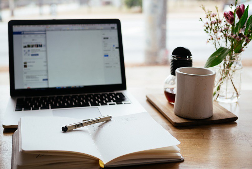 Работна атмосфера за писане на cv автобиография с лаптоп и тефтер.